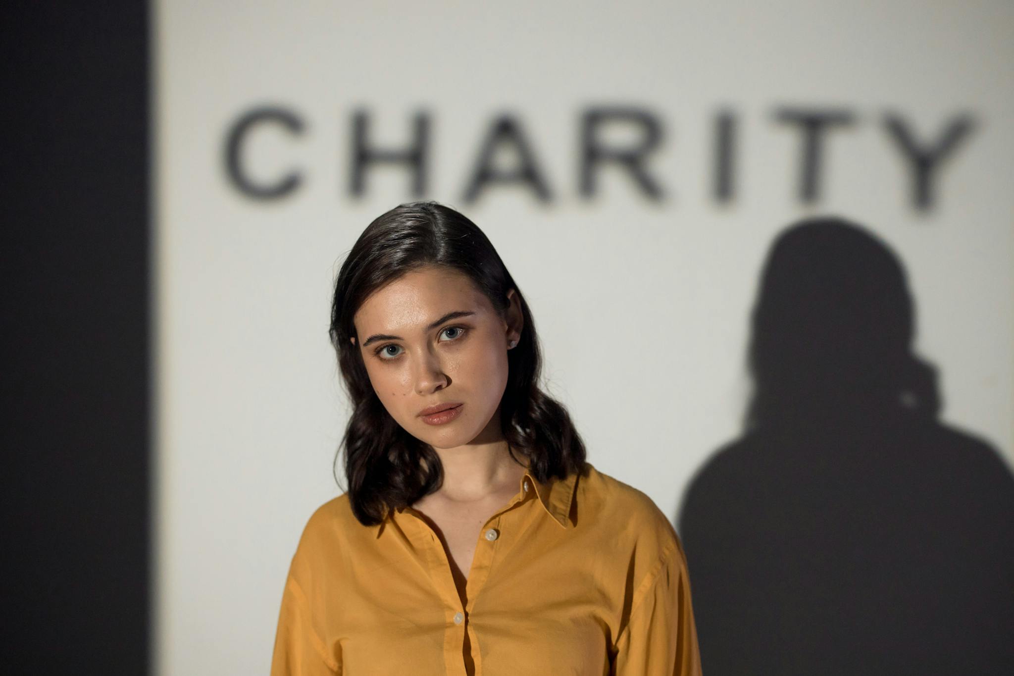 A thoughtful woman stands before a charity-themed backdrop, evoking compassion and volunteerism.